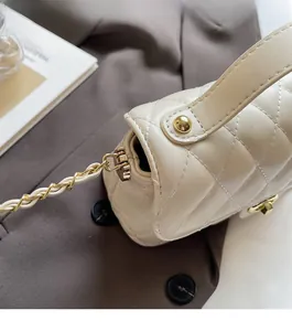 Detail of cream quilted leather handbag with glossy finish and gold metal chain hardware