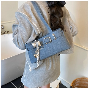 Blue denim shoulder bag featuring buckle detail and butterfly charm shown on a model