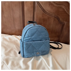 Detail of blue quilted denim mini backpack featuring silver twist lock and leather straps