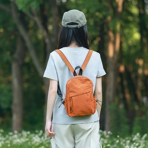 Outdoor view of lightweight orange hiking backpack with adjustable side drawstring pocket