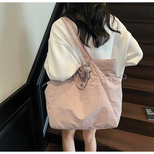 Side view of large pink nylon tote bag on shoulder with drawstring closure details