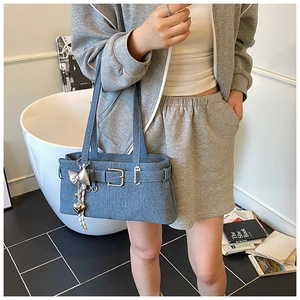 Detail view of denim bucket bag with silver buckle and heart pendant charm