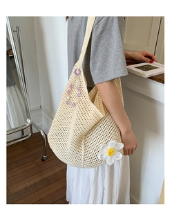 Nahaufnahme des gehäkelten Blumenmusters an einer beigen Strick-Tote-Tasche für Damen
