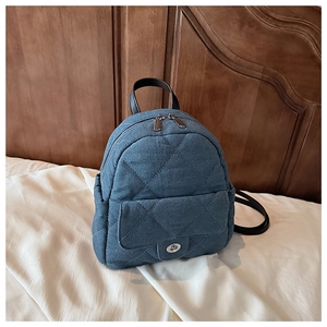 Detail of blue denim mini backpack showing quilted diamond stitching and metal turn-lock