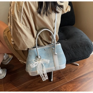 Detailansicht der hellblauen Jeans-Handtasche mit Silberrand und weißer Spitzenschleife