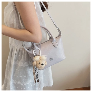 Détail d'un sac bandoulière gris clair minimaliste avec un charmant ours en peluche