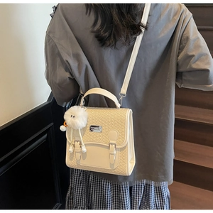 Détail du sac à dos crème avec rabat tissé et charmant pendentif en peluche blanc