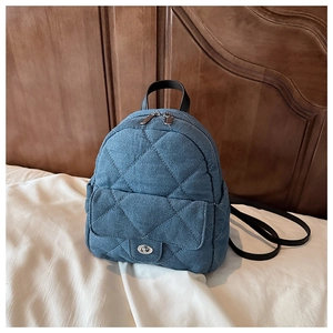Detail of blue denim quilted mini backpack with metal twist lock and chain strap