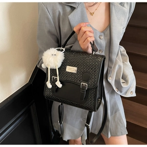 Détail du sac noir à texture tressée avec boucles argentées et breloque en peluche