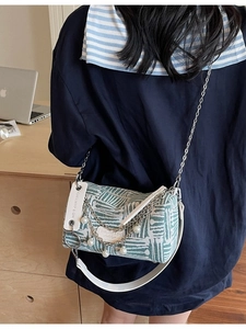Fashionable green jacquard cylinder crossbody bag with pearl chain shown in a daily setting