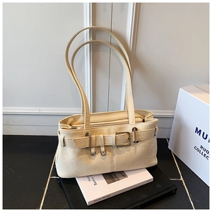 Close-up of beige textured leather bucket bag featuring metal ring and buckle details