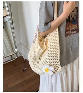 Detail der cremefarbenen Stricktasche mit 3D-Gänseblümchen und lila Perlenanhänger