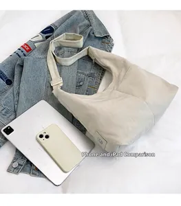 Size comparison of nylon tote bag with tablet and phone on white fabric backdrop