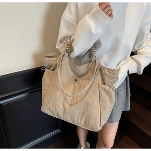 Detail of beige nylon tote bag with thick rope knot handles and side drawstring pockets