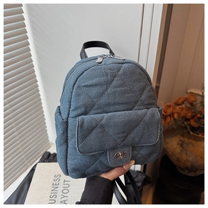 Detail of blue denim backpack with diamond quilting and metallic twist lock closure