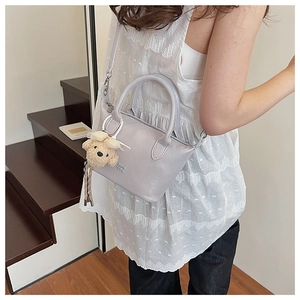 Détail du sac seau en cuir PU lilas avec pendentif ours en peluche et chaîne en perles