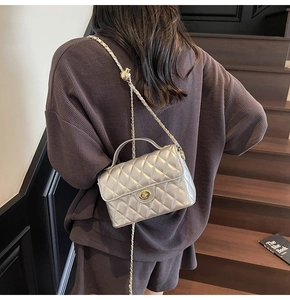 Silver quilted crossbody bag with gold chain and ball detail on model in stairwell