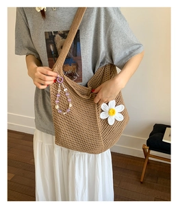 Detail der handgewebten Hobo-Tasche mit weißen Gänseblümchenmustern und Perlenanhänger