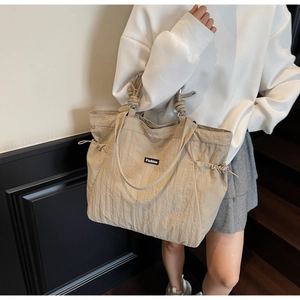 Detail of khaki nylon tote bag showing wrinkled texture and side drawstring design