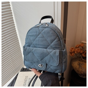 Detail of blue quilted denim mini backpack with silver metal twist lock and chain strap