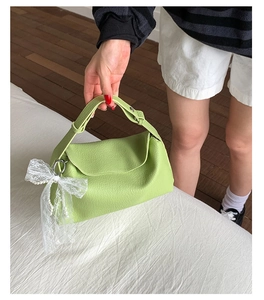Detail of avocado green leather handbag with lace bow and white pearl charm accessory