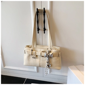 Detail of cream white bucket bag featuring pebble leather texture and silver charms