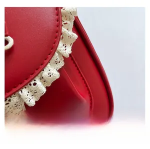 Dettaglio macro della borsa in pelle rossa con bordo in pizzo bianco e trama fine