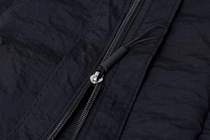 Detail of premium black nylon backpack showing smooth zipper and woven drawstring texture