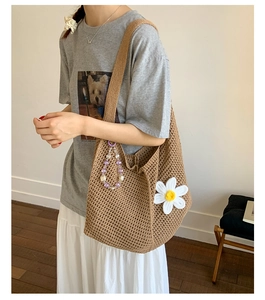 Detail der braunen Häkeltasche mit weißem Gänseblümchen-Dekor und lila Perlenanhänger-Charme