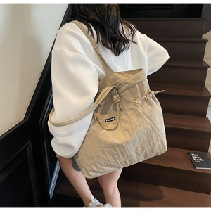 Macro detail of beige nylon tote bag with drawstring closure and Fashion logo patch