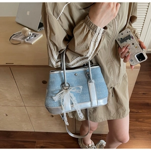 Nahaufnahme der blauen Denim-Beuteltasche mit Strassdekor und weißer Spitzenschleife