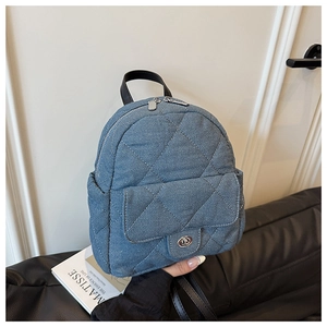 Detail of blue denim quilted backpack with silver twist lock and black leather straps