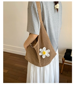 Detail einer braunen Häkel-Einkaufstasche mit weißer Strickblume auf der Modelschulter