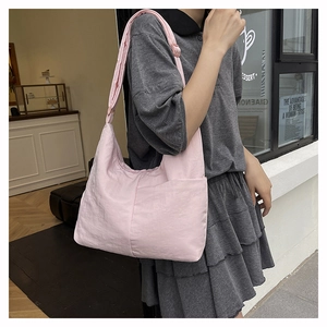 Macro detail of soft pink nylon tote bag showing side pocket and wrinkled fabric texture