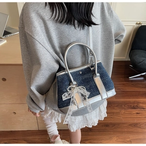 Detailansicht der Eimer-Tasche aus Denim und Silberleder mit Perlen-Schleifen-Anhänger
