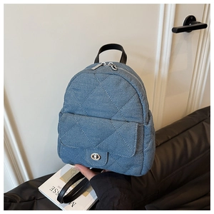 Macro shot of blue denim quilted mini backpack with silver twist lock and leather straps