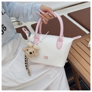 Détails d'un sac à main en cuir blanc avec poignée rose et breloque ours en peluche