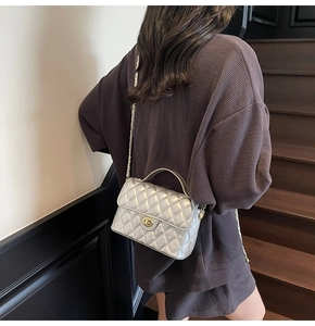 Detail of silver quilted handbag featuring gold twist-lock and elegant metal chain strap