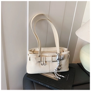 Detail of cream white litchi leather bag with silver bow charm and belt buckle
