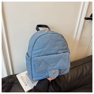 Detailed view of blue denim quilted backpack with silver twist lock and black handle