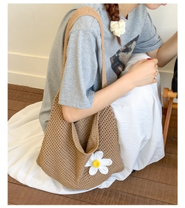 Detail der braun gestrickten Tragetasche mit einer weißen 3D-Häkelblume Gänseblümchen