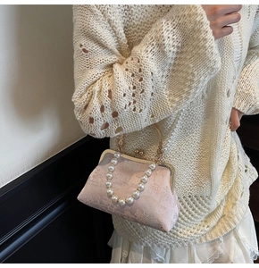 Detailed view of pink brocade fabric with floral embroidery and pearl handle on handbag