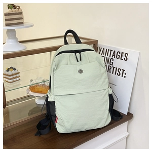 Close-up of light green nylon travel backpack featuring black mesh side pockets and logo