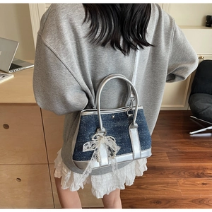 Detail of blue denim bucket bag with sequins and lace pearl bow charm on model
