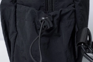 Detailed close-up of nylon backpack showing elastic drawstring and metal D-ring hook