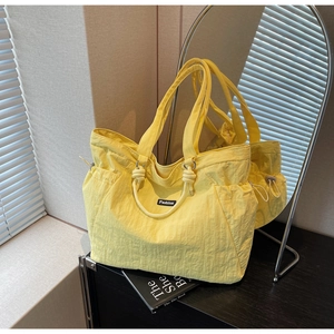 Close-up of vibrant yellow nylon tote bag with drawstring details and Fashion tag