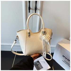 Detail of cream bucket bag with pleated leather texture, pearl heart charm and lace ribbon