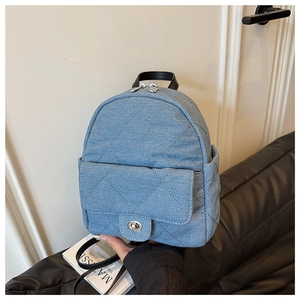 Detail of blue denim mini backpack featuring quilted patterns and metal turn-lock