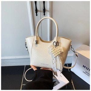 Detail of cream pleated leather bucket bag with pearl heart charm and lace bow decor