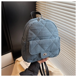 Close-up of blue denim quilted mini backpack featuring silver twist lock and stitch detail